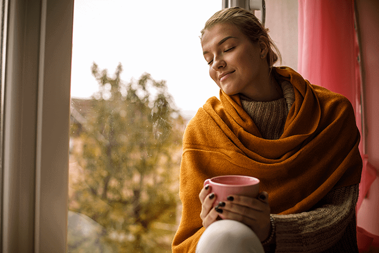 woman by the window in fall with coffee