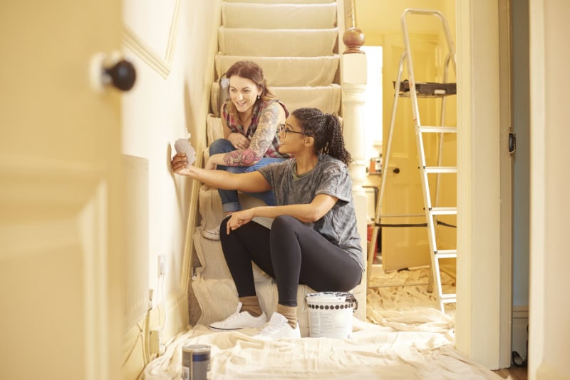 Why Is Remodeling My Home in the Fall or Winter a Better Time. Some ladies have a chat on the stairs to discuss which color to paint the woodwork in their new home.