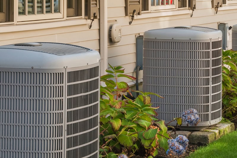 Spring AC Maintenance Tips. Photo of two air conditioning units installed outside of a home.